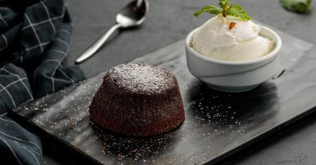 كعكة البراونيز مغطاة بصلصة الشوكوالتة ومرشوشة بالمكسرات مع آيس كريم الفانيال Warm Chocolate Cake